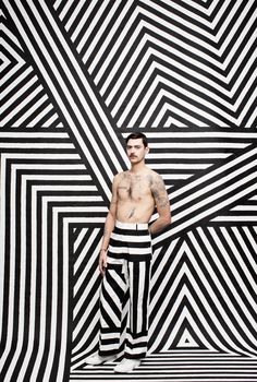 a man standing in front of a black and white striped wall