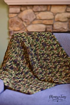 a blanket is sitting on a chair in front of a stone fire place with a fireplace