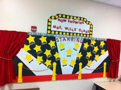 a classroom wall decorated with red curtains and yellow stars on the front, and a sign that says now showing mrs willis class starting