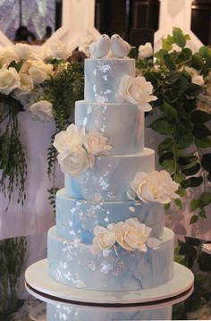 a blue wedding cake with white flowers on it