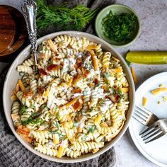 a white bowl filled with pasta and sauce on top of a table next to some vegetables