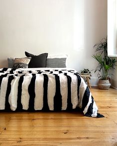 a bed with black and white striped blankets on it in a room next to a window