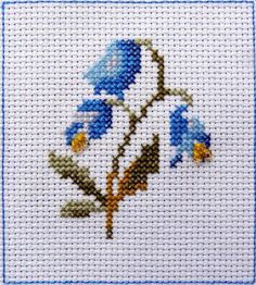 a cross stitch picture with blue flowers on it