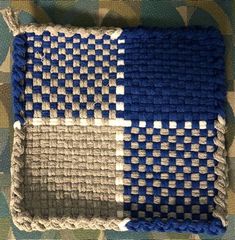 a blue and white crocheted pillow sitting on top of a camouflage print blanket