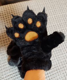 a hand that has some kind of black animal paw on it's palm with yellow eyes