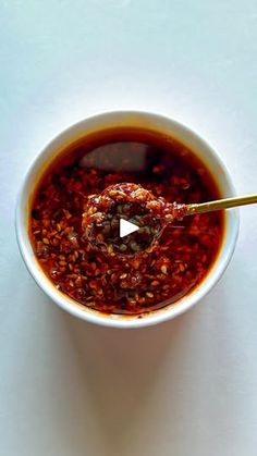 a white bowl filled with red sauce and a wooden spoon in front of the bowl