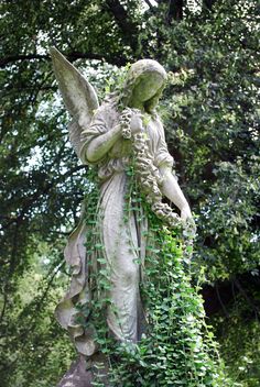 an angel statue with ivy growing around it