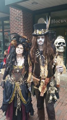 two people dressed up in costumes standing next to each other on a brick walkway outside a store