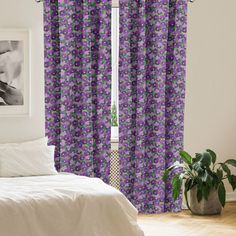 a bed sitting next to a window covered in purple curtains