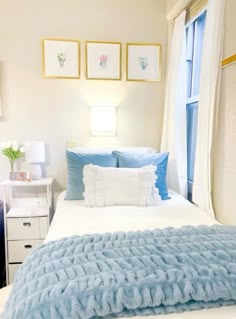 a bedroom with blue and white bedding and pictures on the wall