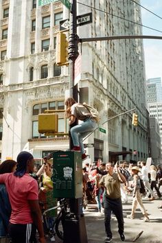 a group of people standing on top of a street light pole next to a tall building