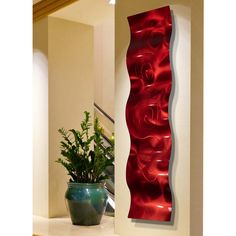 a vase sitting on top of a white counter next to a red wall mounted art piece