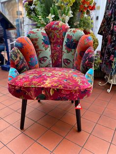 a colorful chair sitting on top of a red tile floor next to a bunch of flowers