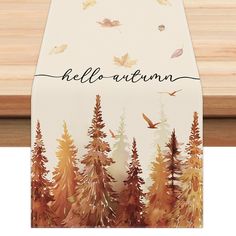 a table runner with autumn trees and leaves on it that says hello autumn in black ink