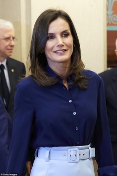 queen letizia of spain wearing a blue shirt and white skirt in the state dining room