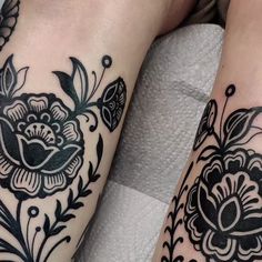 two black and white tattoos on both legs, one with an ornate flower design in the middle