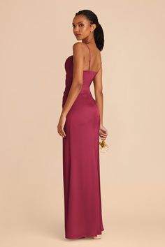 the back of a woman in a pink gown with one shoulder open and her hand on her hip