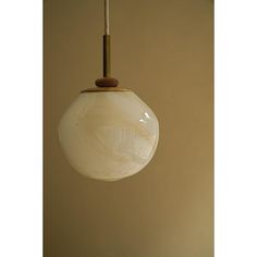 a white glass ball hanging from a brass colored light fixture with a wooden stick sticking out of it