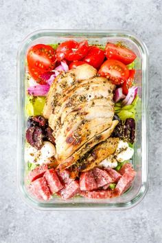 a salad with meat, tomatoes and lettuce in a glass dish on a table