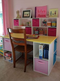 a child's desk and chair in a room with pink walls, carpeted flooring and colorful bins