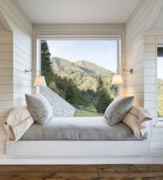 a bed sitting under a window in a bedroom next to a wooden floor and wall