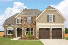 a two story brick house with garages on the front and side windows, surrounded by grass