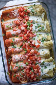 an enchilada dish is topped with tomatoes and cilantro