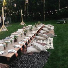 a long table is set up with pillows and place settings for an outdoor dinner party