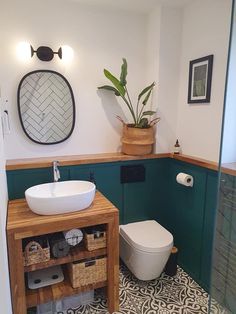 a bathroom with a toilet, sink and mirror in it's corner area on the wall