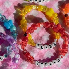 several bracelets with name beads on a pink and white checkered table cloth,