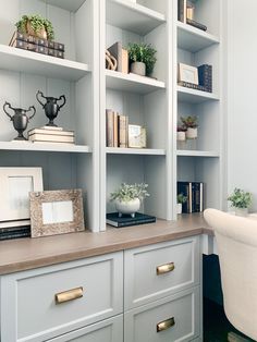 a white chair sitting in front of a book shelf filled with books and other items