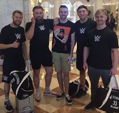 four men are posing with their luggage in the lobby