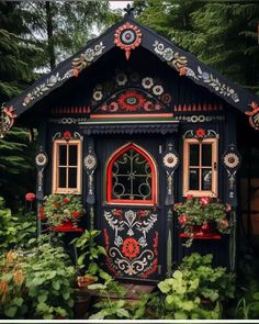 a black and red house in the middle of some trees with plants growing out of it