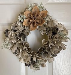 a wreath made out of old book pages and burlocks is hanging on the front door