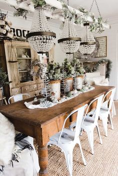 a dining room table with white chairs and chandelier hanging from it's ceiling