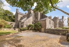 an old stone house with trees in the front yard