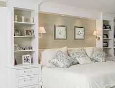 a white bed sitting in a bedroom next to a tall bookcase filled with books