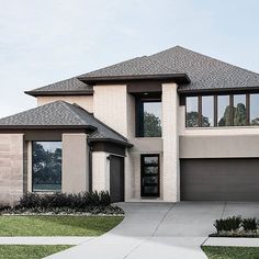 a large house with two garages and windows in the front yard, along side a sidewalk