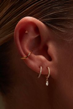 a woman's ear with two small diamond hoops