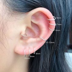 an ear with three different types of piercings attached to the end of each ear