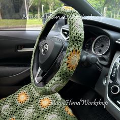 the steering wheel cover is crocheted with flowers and has a sunflower on it