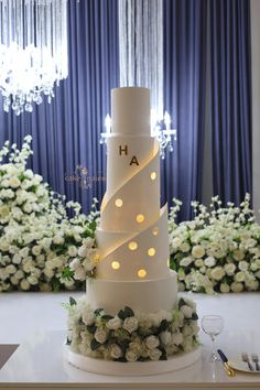 a white wedding cake with lights on it