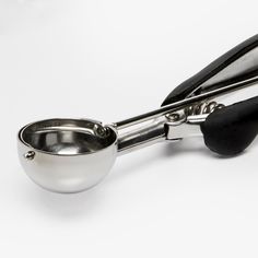 a stainless steel measuring spoon with black handles