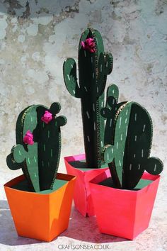 three paper cactus plants in different colors and sizes, one with pink flowers on it