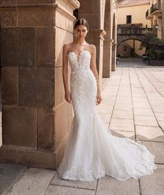 a woman in a wedding dress leaning against a wall