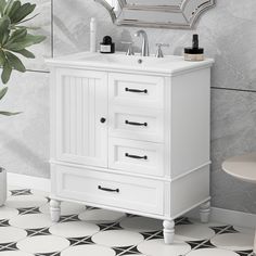 a white bathroom vanity sitting next to a mirror and potted plant on the floor