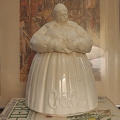 a white cookie jar sitting on top of a table next to a framed photo and book