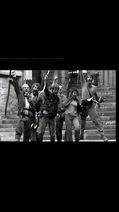 black and white photograph of people on steps with arms in the air holding baseball bats