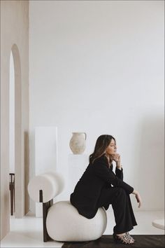 a woman sitting on top of a white chair