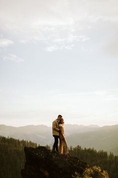 a man and woman standing on top of a mountain